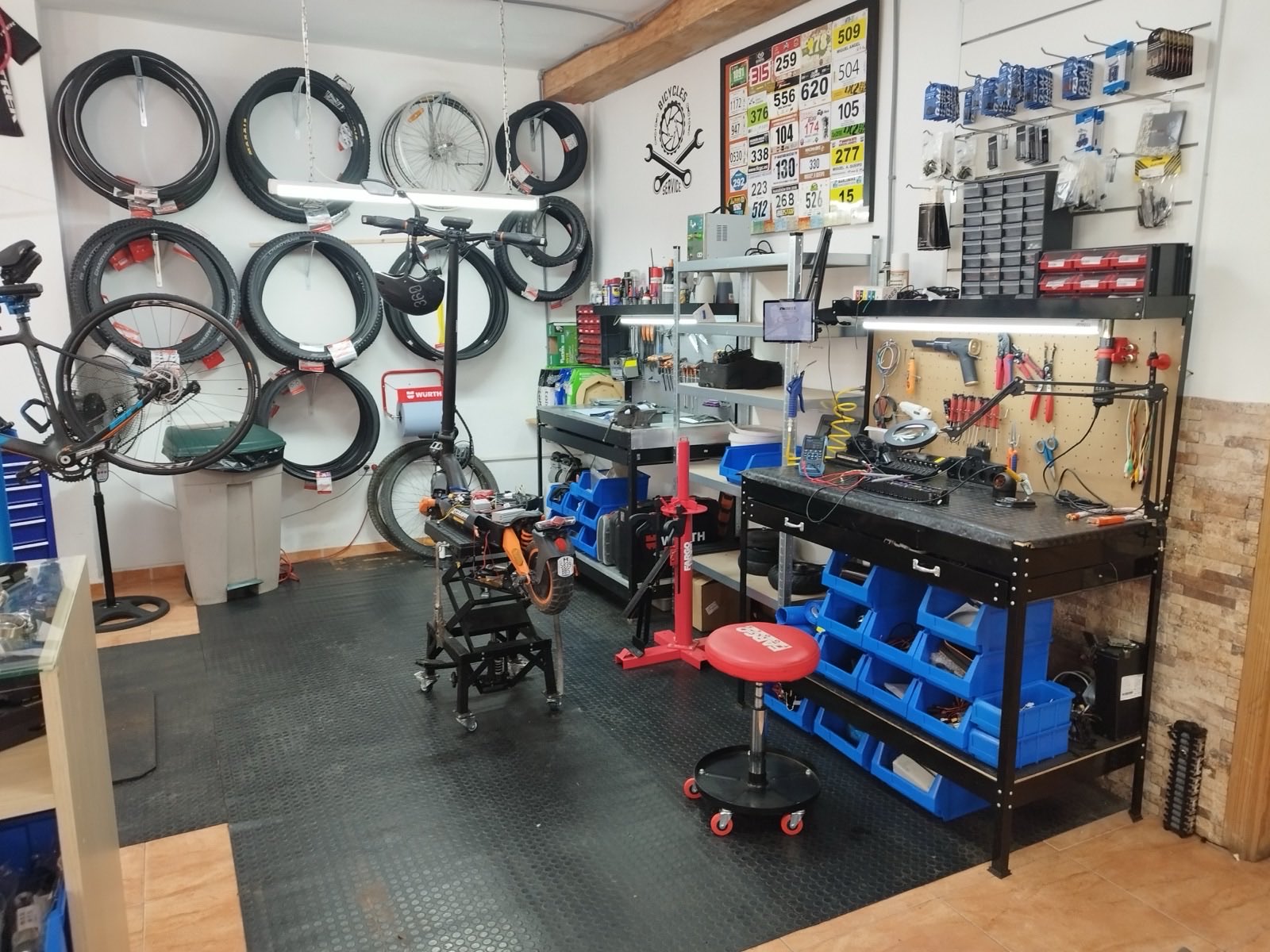 Vista general del taller QR Bike Service con neumáticos, dorsales y banco de trabajo